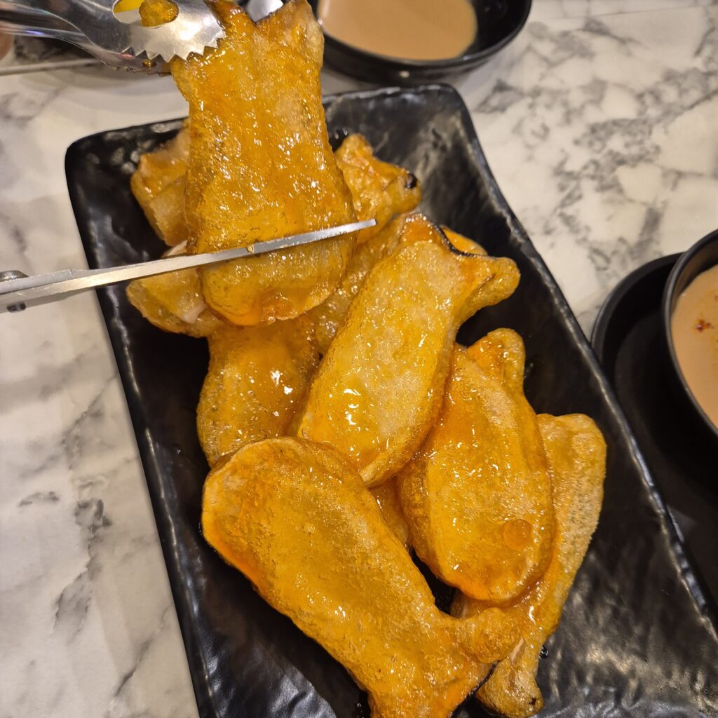 새송이를 길게 편썰어 조리한 버섯 탕수를 가위로 자르고 있다.