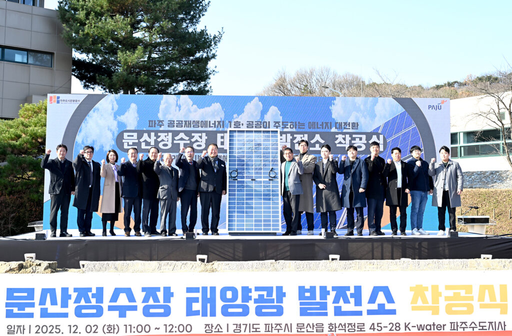 파주시 문산정수장 태양광 발전소 착공식 사진. 참가자들이 태양광 패널 옆에 서있다.