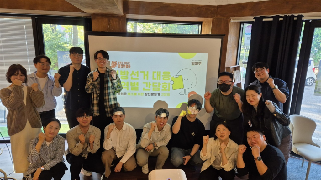 대전 청년공간에서 열린 '불평등물어가는범청년행동 개최 충청권 지역 활동가 간담회' 기념 사진. 참석한 청년 활동가들이 '지방선거 대응 권역별 간담회 간담회'라는 문구가 적힌 빔프로젝터 화면을 배경으로 두고 서서, 카메라를 바라보며 다 함께 한쪽 주먹을 쥐고 파이팅 포즈를 취하고 있다.