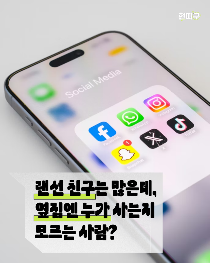 스마트폰 화면에 인스타그램, 페이스북, 왓츠앱, 틱톡 등 SNS 앱 아이콘이 보인다. 하단 말풍선 형태 박스에는 “랜선 친구는 많은데, 옆집엔 누가 사는지 모르는 사람?”이라는 문구가 적혀 있다. 우측 상단에는 ‘현따구’ 로고가 있다.
